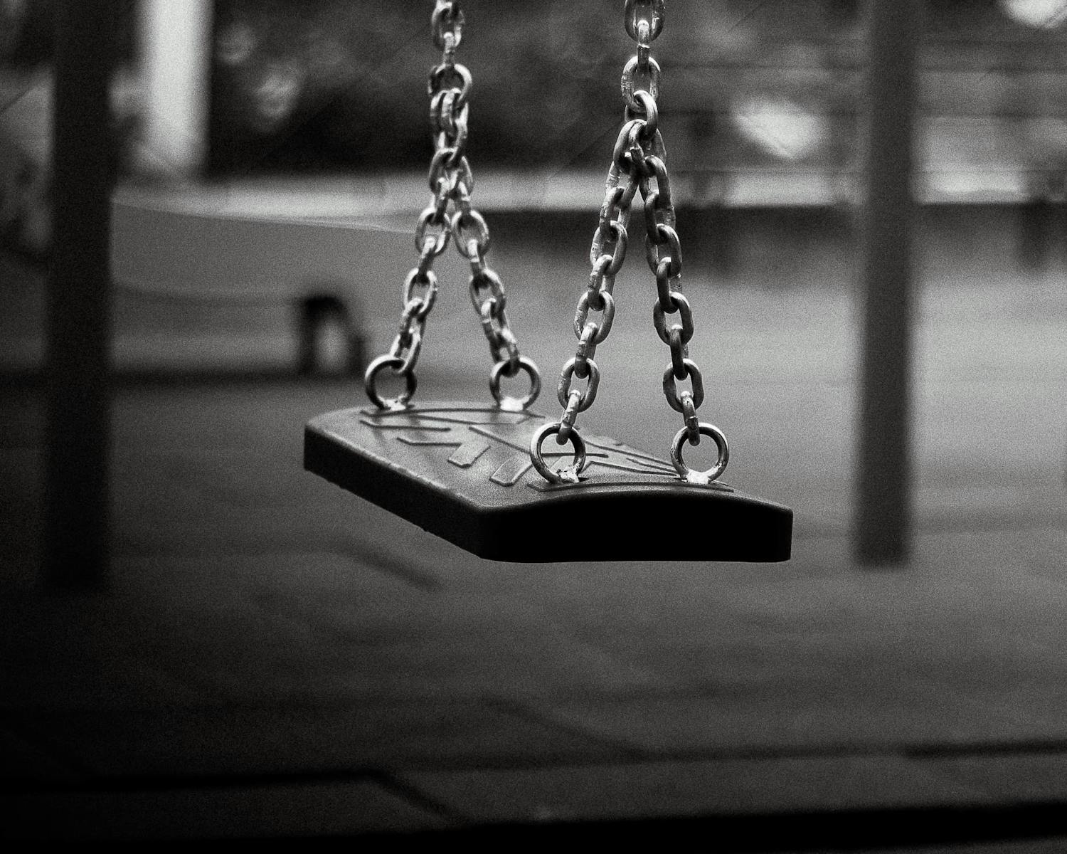 Lonely swing in a deserted playground, captured in striking black and white.